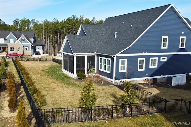 back of house featuring a lawn, a sunroom, a fenced backyard, roof with shingles, and central air condition unit