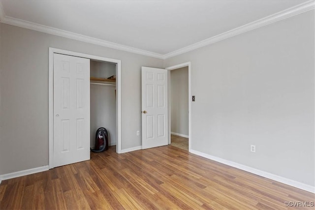 unfurnished bedroom featuring hardwood / wood-style flooring, ornamental molding, and a closet