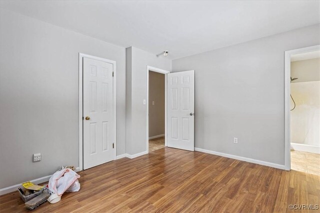 unfurnished bedroom with connected bathroom and hardwood / wood-style floors