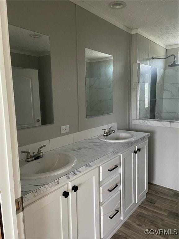 bathroom featuring a textured ceiling, vanity, a shower, ornamental molding, and hardwood / wood-style flooring