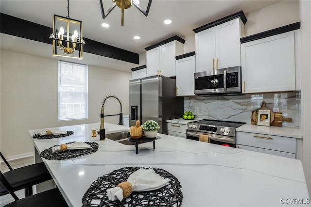 kitchen featuring light stone counters, tasteful backsplash, pendant lighting, and appliances with stainless steel finishes