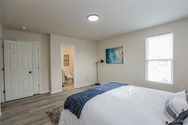 bedroom with light hardwood / wood-style flooring, multiple windows, and ensuite bath