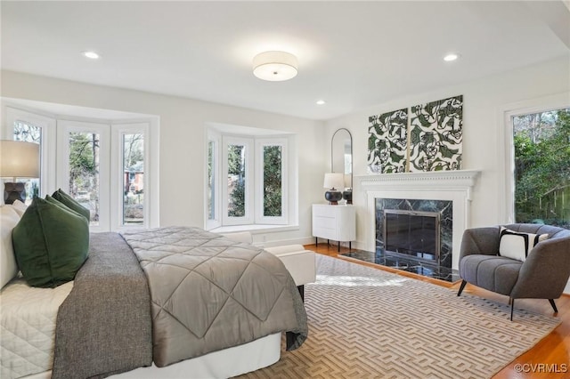 bedroom with hardwood / wood-style flooring and a high end fireplace