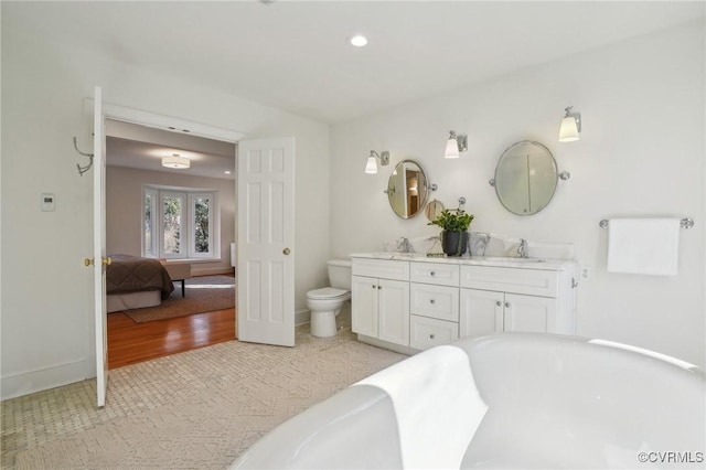 bathroom with vanity, hardwood / wood-style flooring, a tub to relax in, and toilet