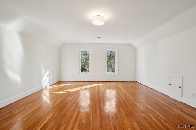 bonus room with lofted ceiling and light wood-type flooring