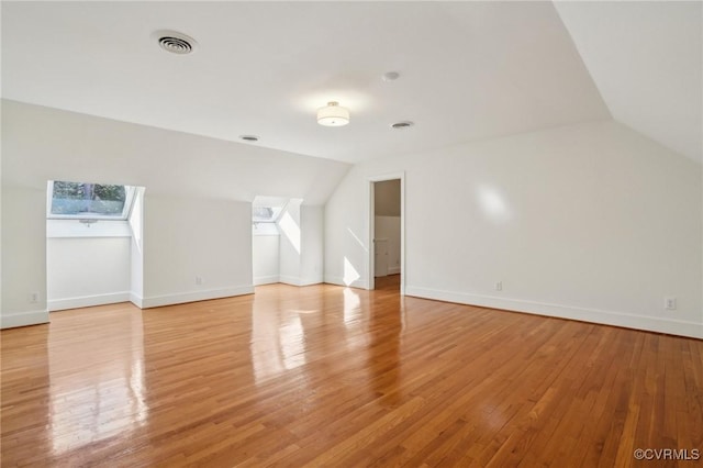 bonus room with light hardwood / wood-style floors and vaulted ceiling with skylight