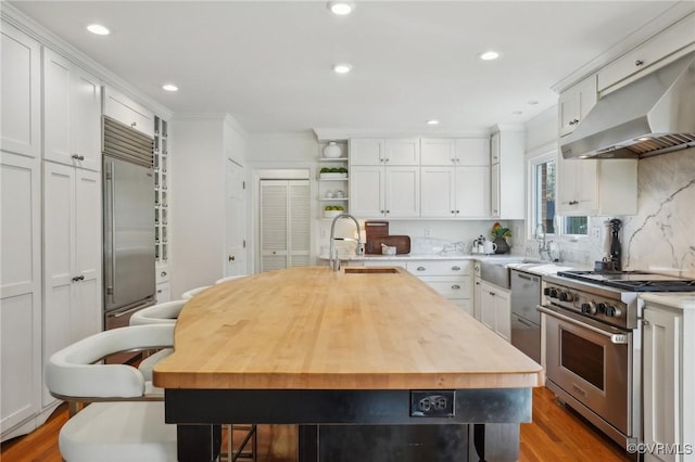 kitchen featuring premium appliances, white cabinets, and an island with sink