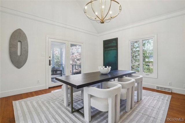 dining area with hardwood / wood-style floors, crown molding, lofted ceiling, and an inviting chandelier