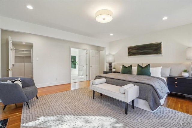 bedroom featuring a closet, ensuite bathroom, a spacious closet, and hardwood / wood-style floors