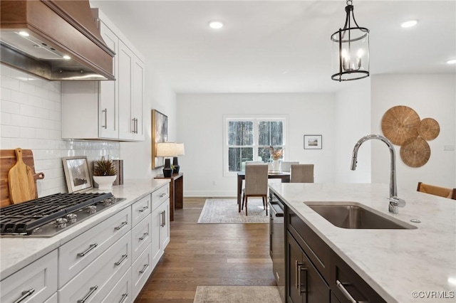 kitchen with stainless steel gas stovetop, custom exhaust hood, sink, decorative light fixtures, and white cabinetry