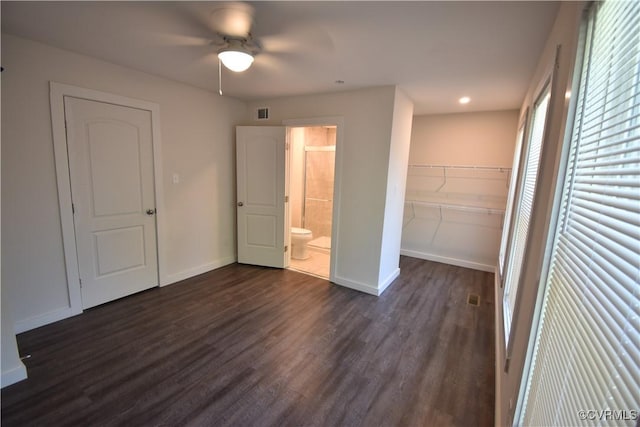 unfurnished bedroom with a closet, ceiling fan, dark wood-type flooring, and ensuite bath