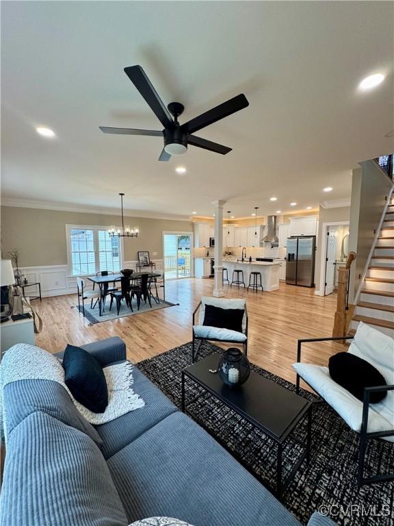 living area with stairs, wainscoting, light wood-style flooring, and crown molding