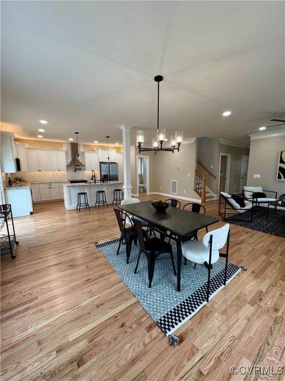 dining room featuring a chandelier, recessed lighting, visible vents, light wood finished floors, and ornate columns