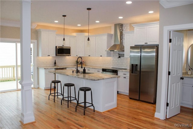 kitchen featuring stainless steel appliances, white cabinetry, and wall chimney range hood