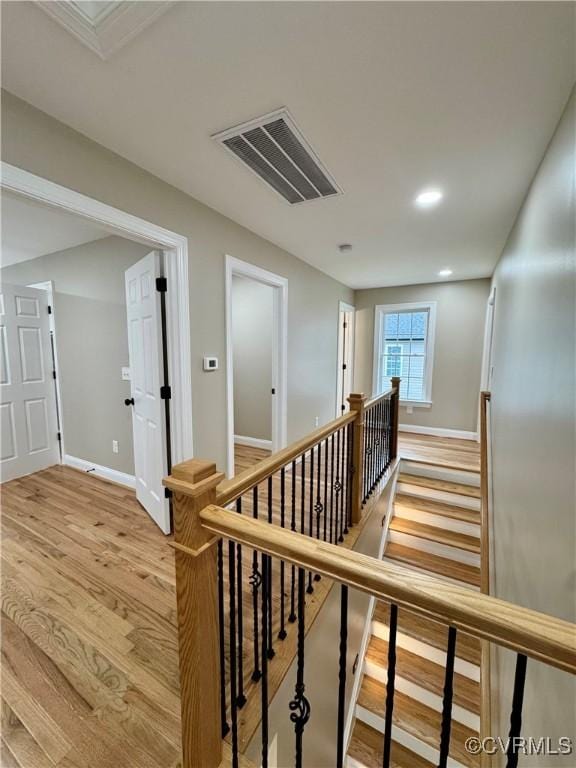 corridor featuring recessed lighting, wood finished floors, visible vents, an upstairs landing, and baseboards