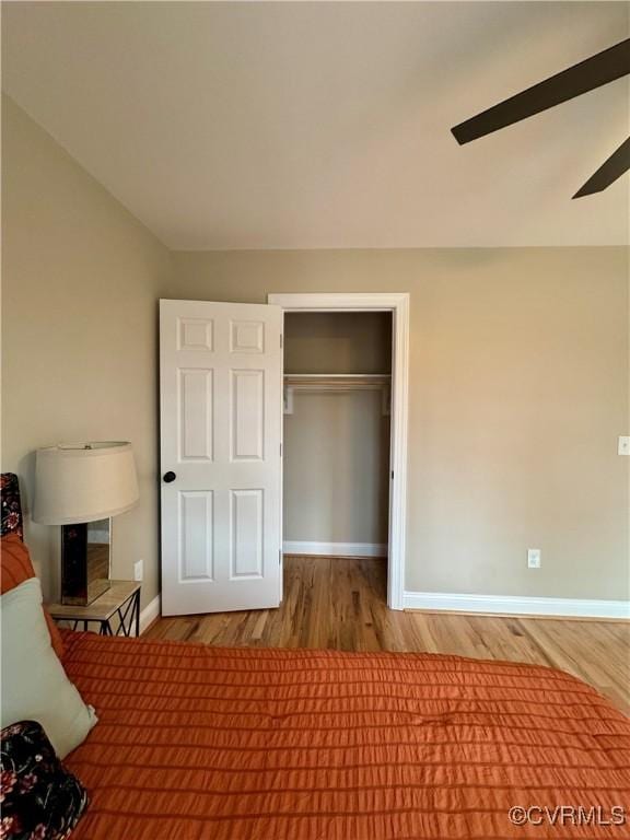 unfurnished bedroom featuring ceiling fan, a closet, wood finished floors, and baseboards