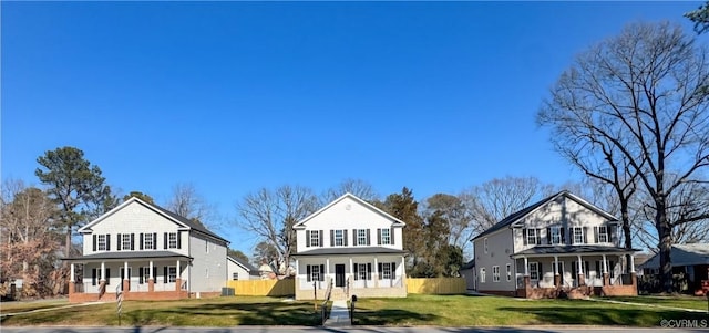 traditional-style house featuring fence, a porch, and a front yard