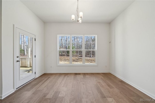 unfurnished dining area featuring a chandelier, light hardwood / wood-style flooring, and a wealth of natural light