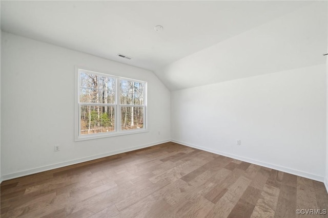 additional living space featuring vaulted ceiling and hardwood / wood-style flooring