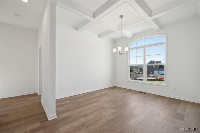 empty room featuring wood-type flooring, beam ceiling, a chandelier, and coffered ceiling