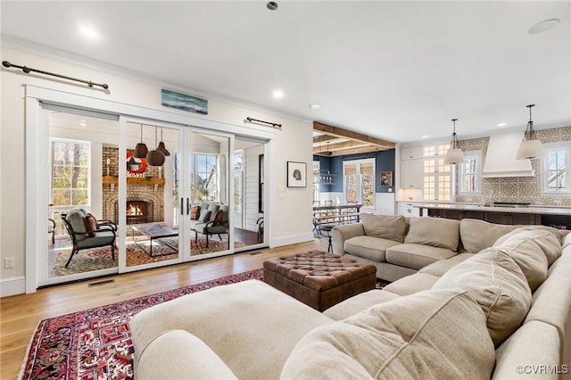 living area with visible vents, baseboards, light wood finished floors, recessed lighting, and a fireplace