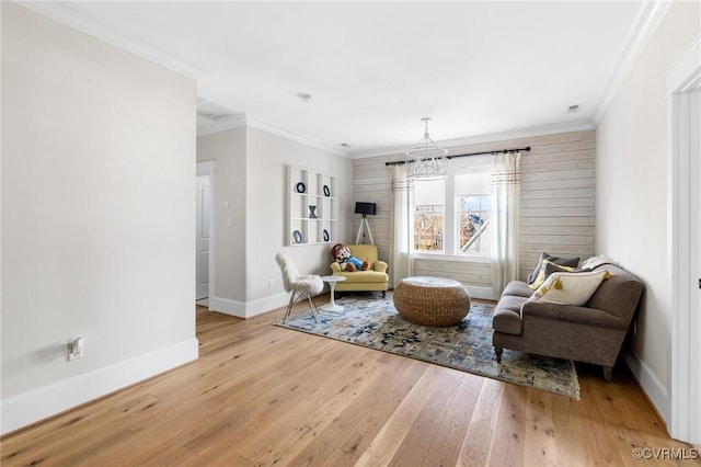 living area with a notable chandelier, ornamental molding, and light wood-type flooring