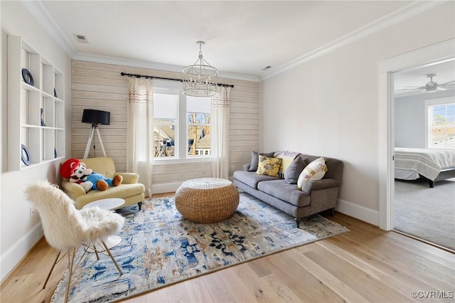 living area with crown molding and light hardwood / wood-style flooring