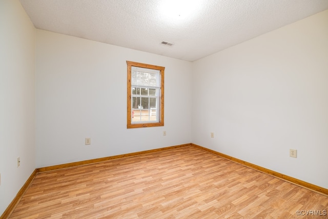 spare room featuring a textured ceiling and light wood-type flooring