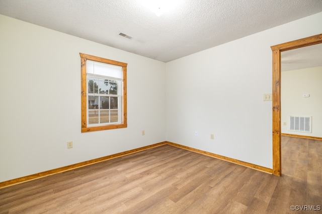 unfurnished room with a textured ceiling and light wood-type flooring