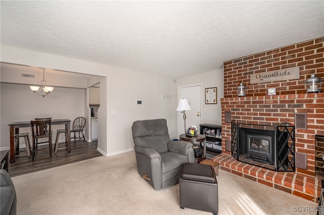 living room featuring a fireplace, a textured ceiling, a chandelier, and carpet flooring