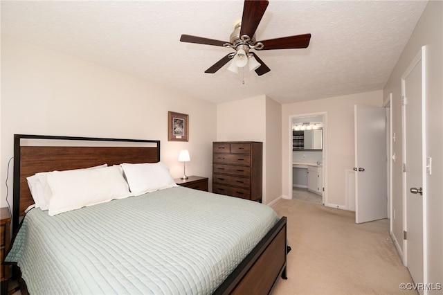 bedroom featuring light carpet, a textured ceiling, ensuite bath, and ceiling fan