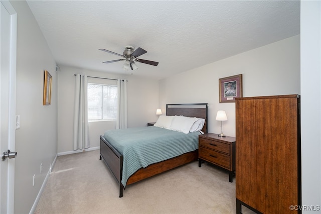 bedroom featuring a textured ceiling, light colored carpet, and ceiling fan