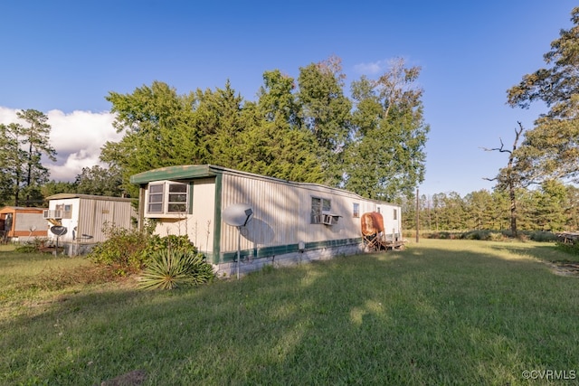 view of side of home with cooling unit, a yard, and an outbuilding