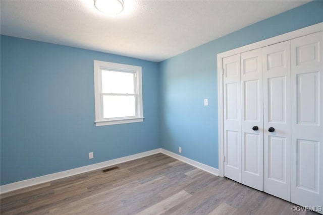 unfurnished bedroom featuring light hardwood / wood-style floors and a closet