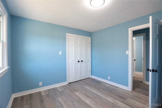 unfurnished bedroom with light hardwood / wood-style flooring, a closet, and a textured ceiling