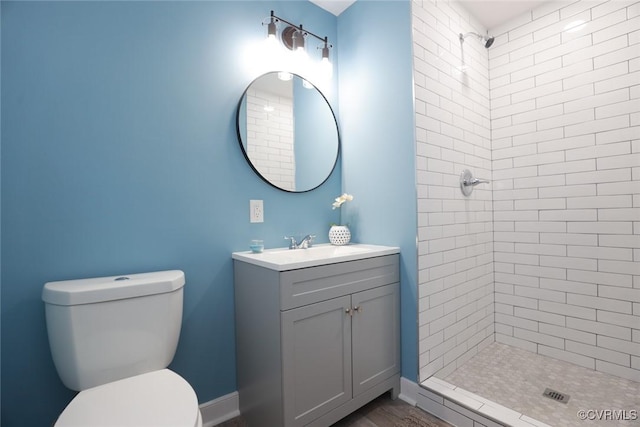 bathroom featuring tiled shower, vanity, and toilet