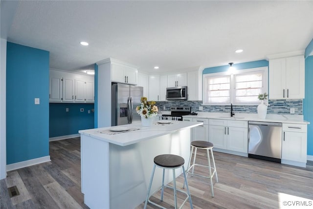 kitchen featuring white cabinetry, sink, a kitchen breakfast bar, a center island, and stainless steel appliances