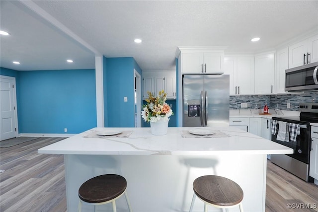 kitchen with appliances with stainless steel finishes, a kitchen breakfast bar, and a kitchen island