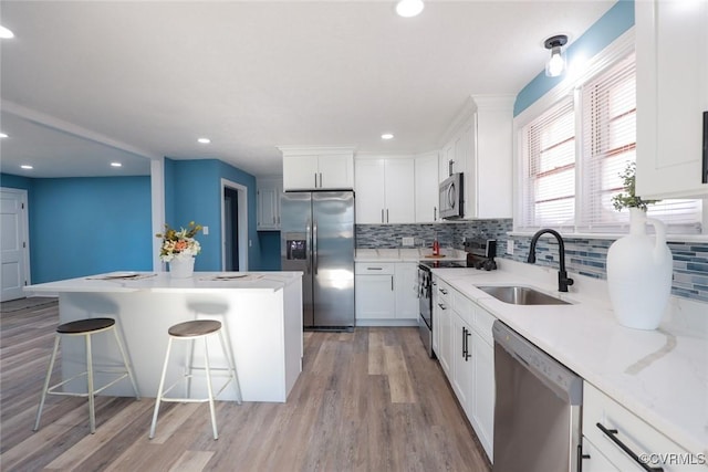 kitchen with a breakfast bar, sink, a center island, appliances with stainless steel finishes, and white cabinets