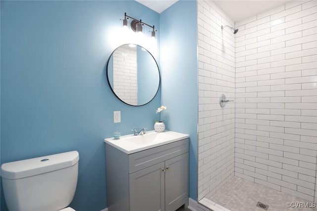 bathroom with vanity, a tile shower, and toilet