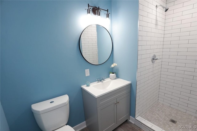 bathroom with vanity, toilet, and a tile shower