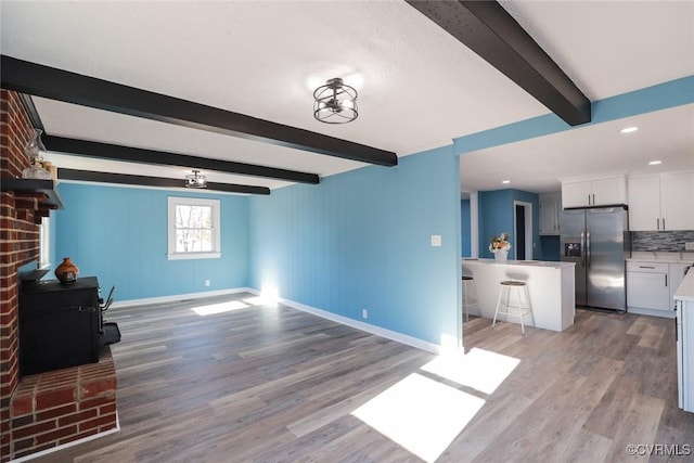 unfurnished living room featuring beam ceiling and light wood-type flooring