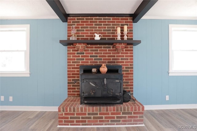 interior details featuring hardwood / wood-style flooring, beamed ceiling, and a wood stove