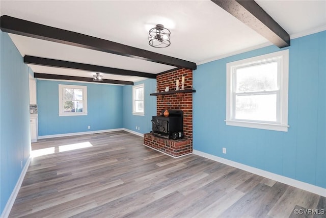 unfurnished living room with beamed ceiling, hardwood / wood-style flooring, and a wood stove