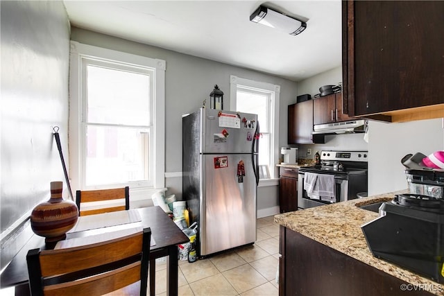 kitchen featuring light stone countertops, light tile patterned flooring, appliances with stainless steel finishes, and dark brown cabinetry