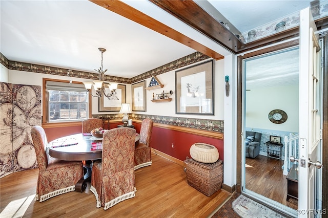 dining area featuring a notable chandelier, beam ceiling, and wood-type flooring