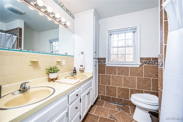 bathroom featuring tile walls, vanity, and toilet