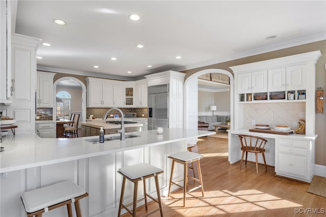 kitchen with a kitchen bar, sink, stainless steel built in fridge, kitchen peninsula, and white cabinets