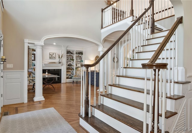 foyer with hardwood / wood-style floors, a towering ceiling, and ornate columns