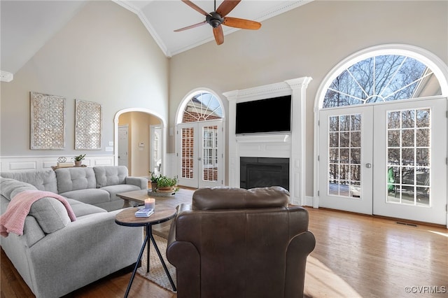 living room featuring light hardwood / wood-style flooring, high vaulted ceiling, french doors, and ceiling fan